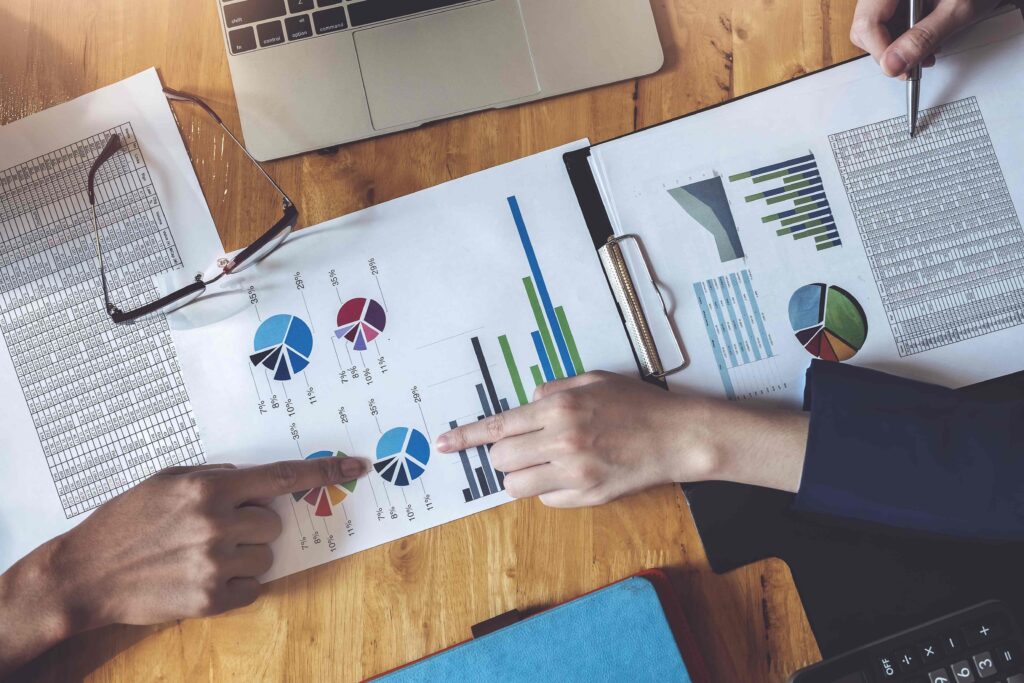 Business people point to documents that have graphs showing the