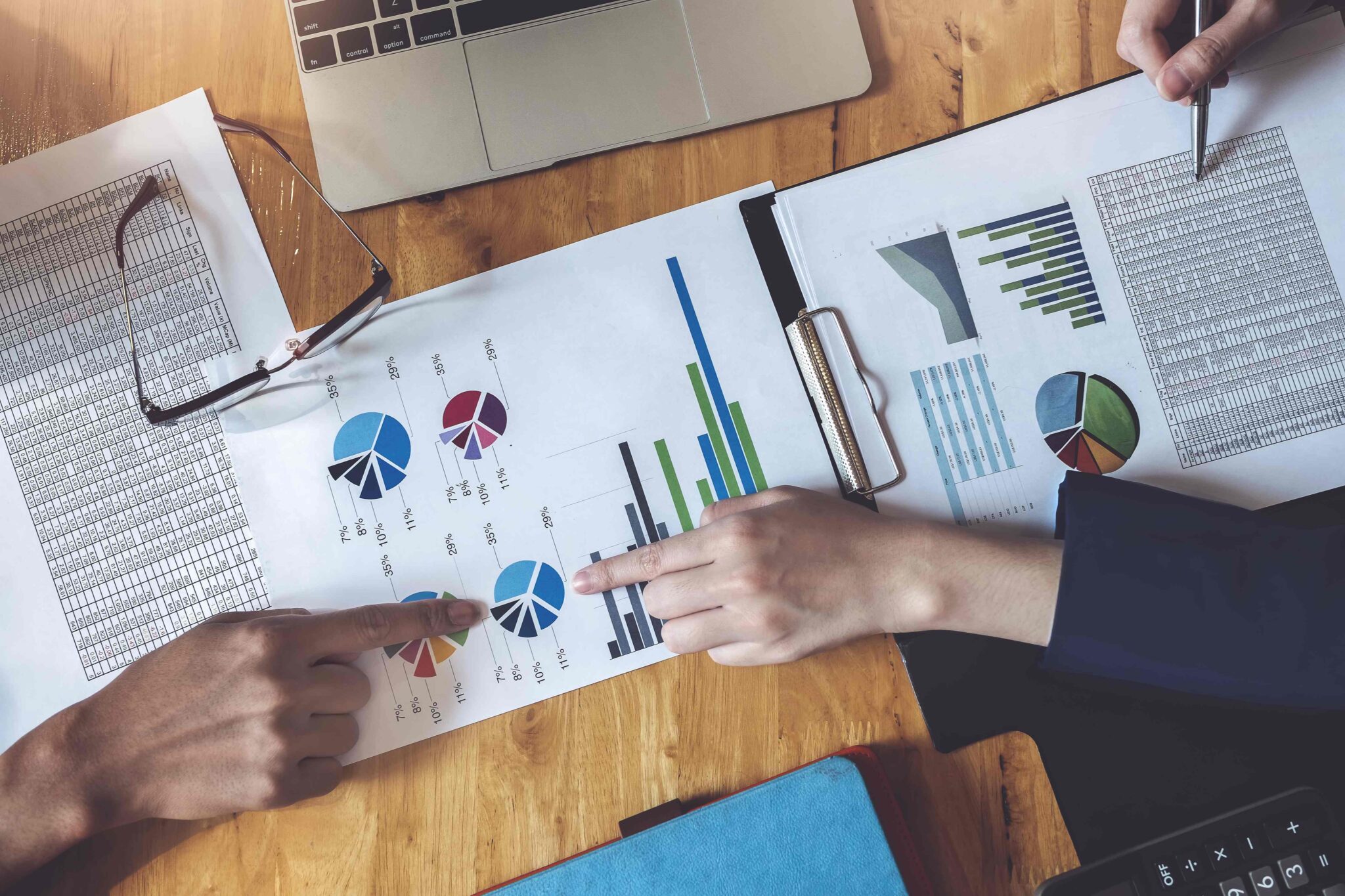 Business people point to documents that have graphs showing the